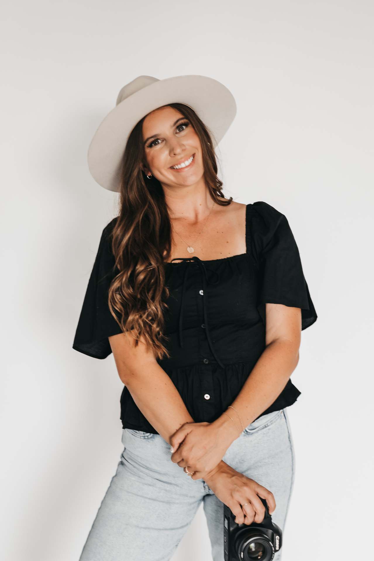 Michelle Johnson, photographer, wearing a cream wide-brim hat and holding her Canon camera