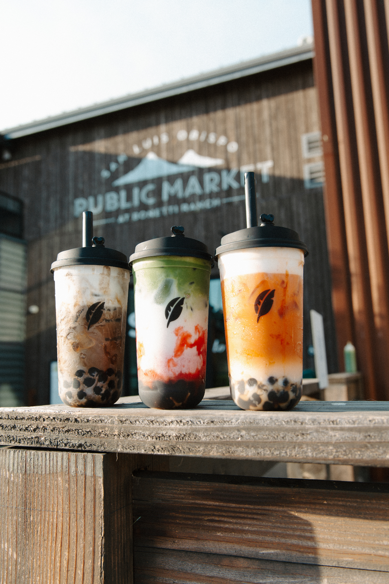 Three boba teas with brand logo lined up in front of the San Luis Obispo Public Market
