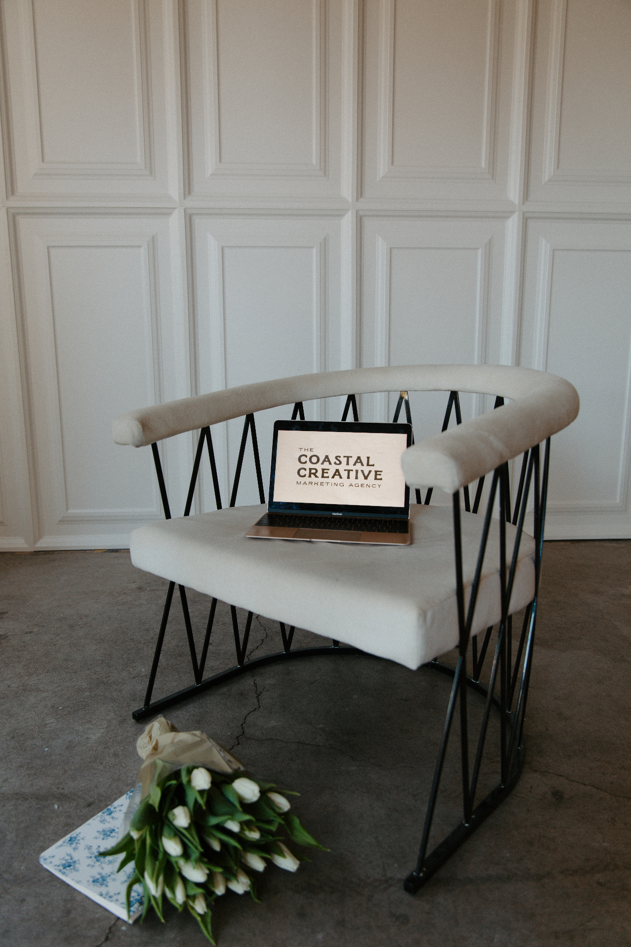 Coastal Creative Marketing Agency branding flatlay with laptop on a velvet chair and white tulip bouquet