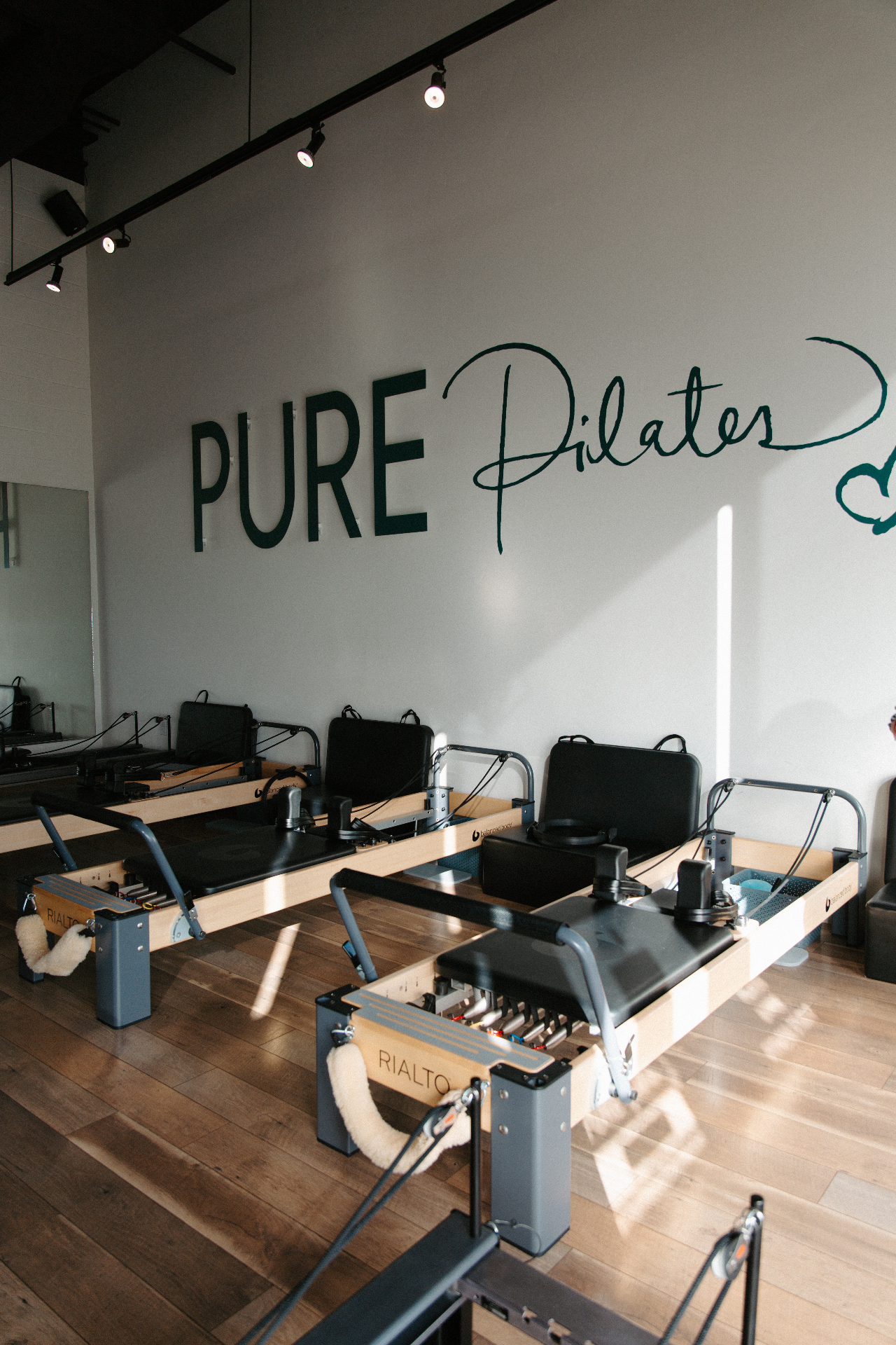 Sunlit Pure Pilates studio interior with reformer machines and signature wall logo
