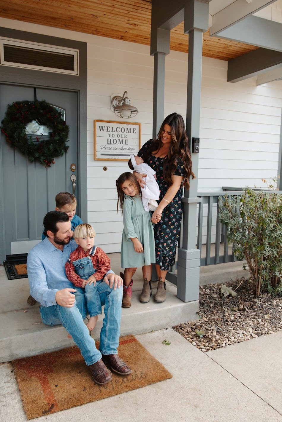 Family of six gathered together on the front porch of their home with a newborn