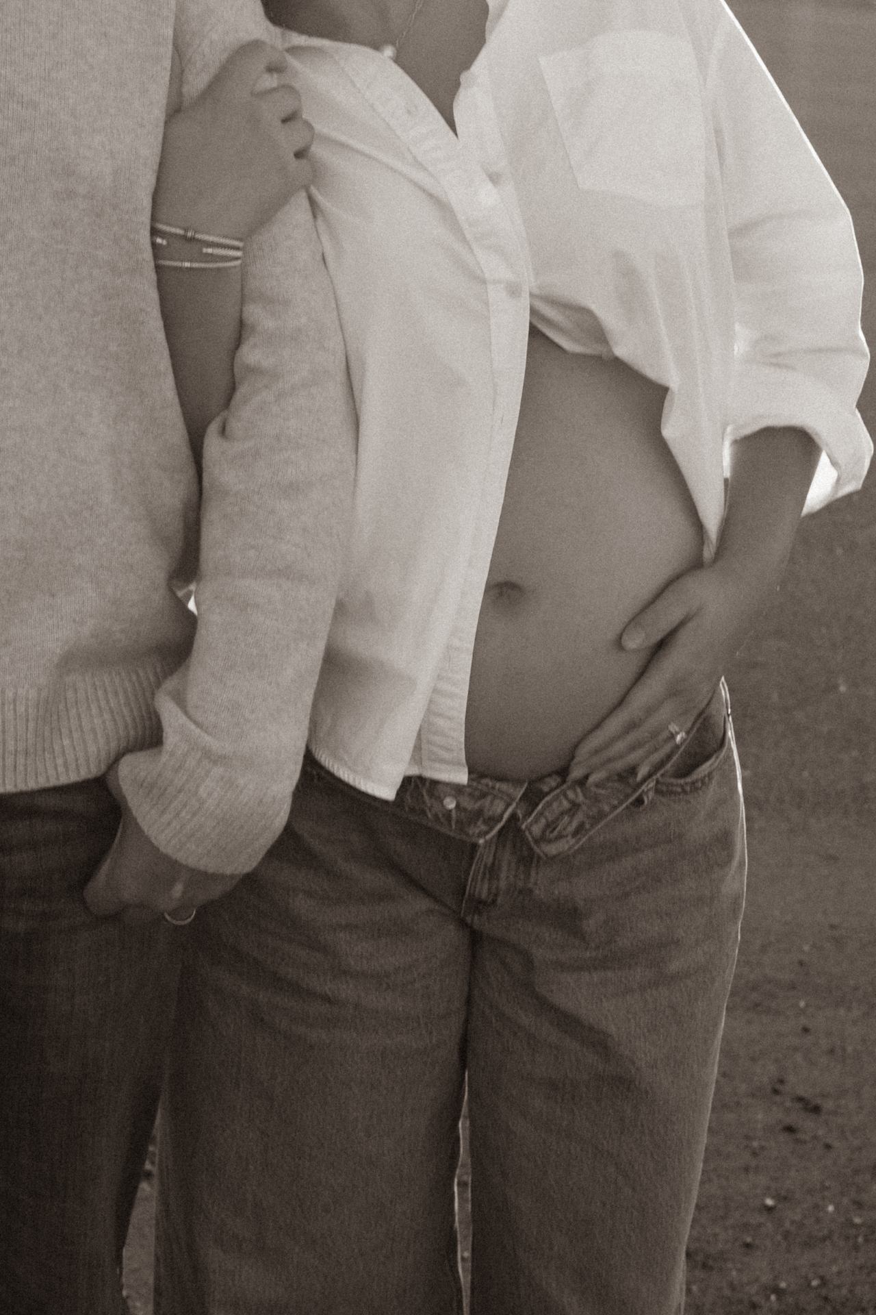 Intimate black and white close-up of a couple holding the baby bump